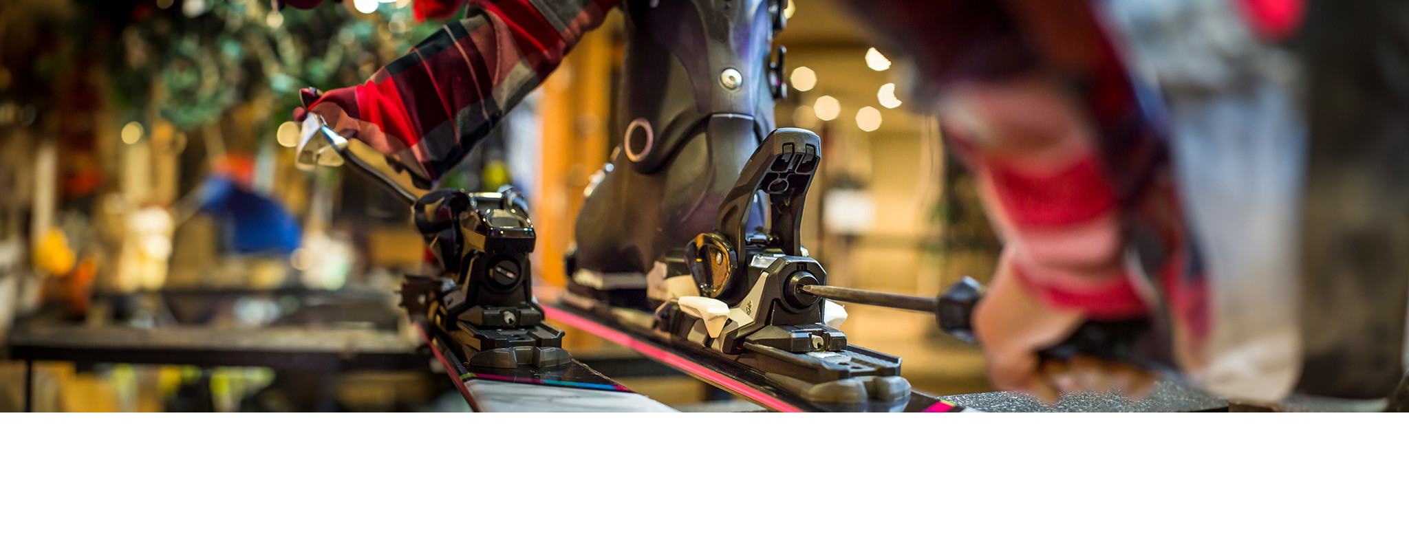 Ski and board servicing. A person adjusting ski binding in a workshop